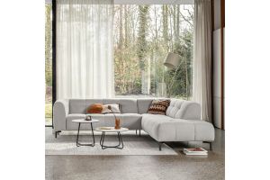 Moderne witte hoekbank in lichte woonkamer met grote ramen, ronde salontafels en sfeervolle accessoires