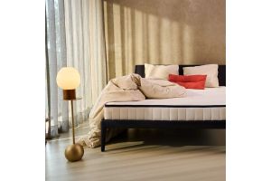 Auping bed en matras in moderne slaapkamer met beige beddengoed en design vloerlamp