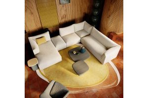 Moderne Pode hoekbank in lichte stof op een warm interieur met ronde vormen en design salontafels