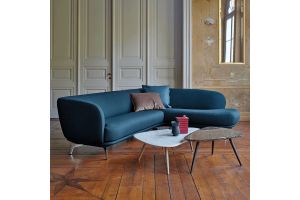 Blauwe, organisch gevormde hoekbank in stof met sierkussens en twee salontafels op een houten vloer in een klassieke interieursetting