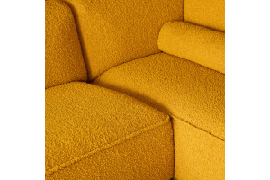 Close-up van bouclé stof van Leolux in warme okergele kleur op designbank met zachte textuur.