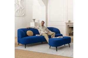 Man ontspannen zittend op een moderne blauwe designbank met bijpassende hocker in een stijlvolle woonkamer