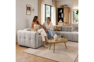 Moderne woonkamer met lichte modulaire hoekbank, ronde salontafel en houten kast in een warm en natuurlijk interieur.
