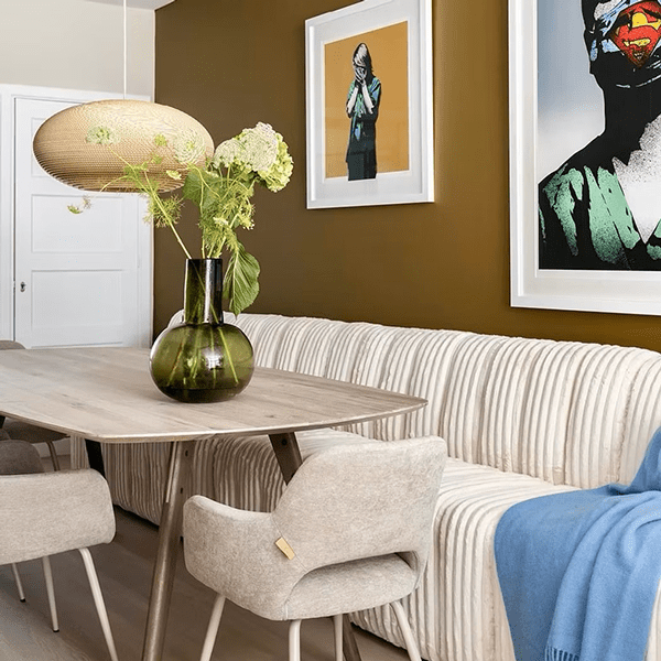 Eetkamer met een moderne houten NOGA-eettafel, omringd door stoelen in neutrale tinten, geplaatst in een sfeervol ingerichte ruimte met warme verlichting.