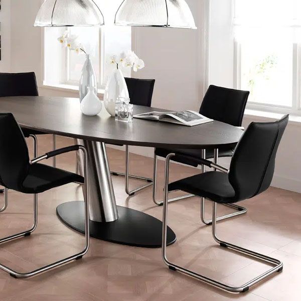 Moderne eetkamer met ovale donkere eettafel, zwarte stoelen met metalen frame en design hanglampen boven de tafel