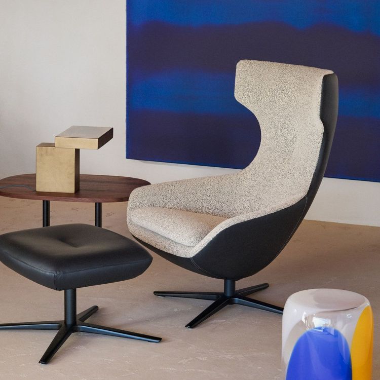 Leolux Caruzzo fauteuil in beige met zwarte buitenzijde en bijpassende poef, met de tekst "Caruzzo nu met poef cadeau".