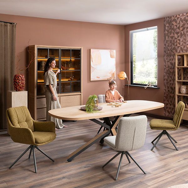 Sfeervolle eetkamer met ovale houten eettafel, draaibare eetkamerstoelen, vitrinekast en warme aardetinten in een modern interieur.