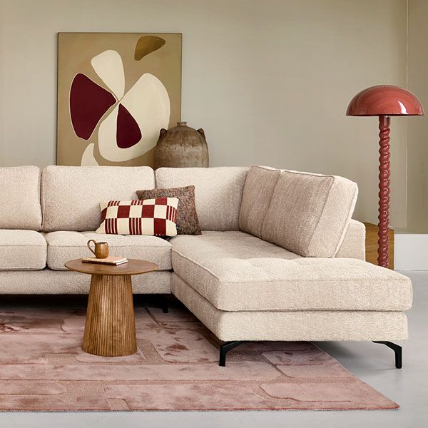INHOUSE hoekbank in beige stof met chaise longue, gecombineerd met ronde houten salontafel en moderne rode vloerlamp in warme woonkamer
