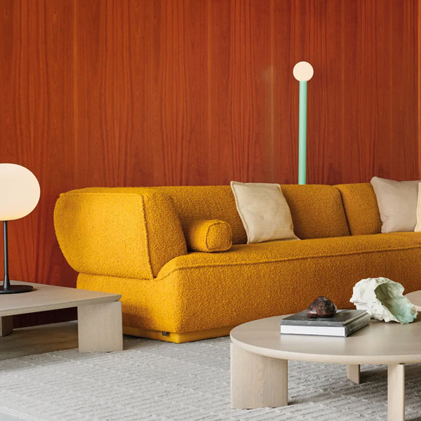 Leolux Loya bank in okergele bouclé stof in modern interieur met warme houten wand en design salontafel