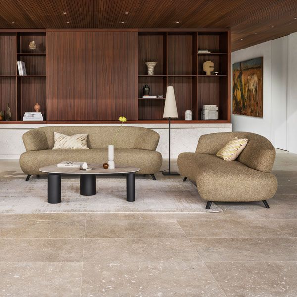 Montèl designbank Bloom en fauteuil in warme taupekleur opgesteld rond een moderne salontafel in een stijlvol interieur met houten wandkast.