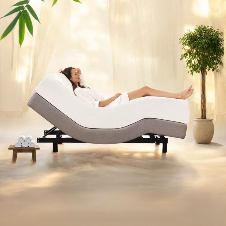 Vrouw die ontspant op een elektrisch verstelbaar Tempur bed in zero gravity positie in een rustige wellness slaapkamer met planten