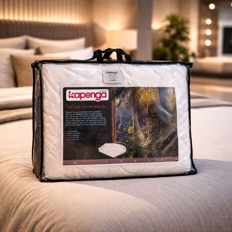 Kapenga Tencel zomerdekbed in draagtas op een bed in een sfeervolle slaapkamer met warme verlichting op de achtergrond