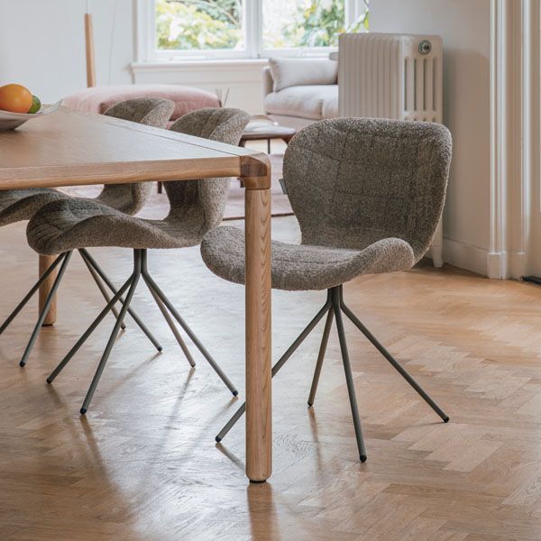 Eetkamer met houten eettafel en twee grijs gemêleerde draaibare eetkamerstoelen met metalen spinpoot op visgraatvloer in lichte, moderne woonkamer.