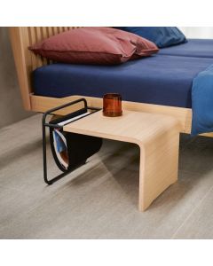 Auping Noa nachttafeltje van licht eikenfineer met zwart stalen frame en vilten magazinehouder naast houten bed