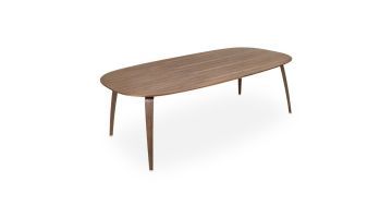 Perspectief aanzicht op witte achtergrond van de ellipsvormige eettafel Gubi, uitgevoerd in donker walnoothout.