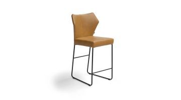 Bree's New World Barkruk Fly Medium bruin leder. De rugleuning heeft aan de zijkant een kleine puntige afwerking en staat op zwart metalen poten.