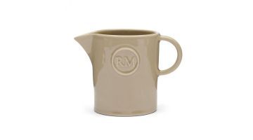 Lichtbruine keramische melkkan met RM-logo, klassieke vorm met schenktuit en oor, tegen een witte achtergrond gefotografeerd.