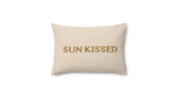 Rechthoekige kussenhoes in beige met de tekst 'SUN KISSED' geborduurd in goudkleurige letters, tegen een witte achtergrond.
