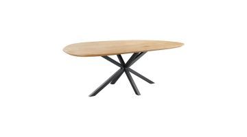 Eettafel Tavolo van Pronto Wonen, schuin vooraanzicht – Een grote eettafel met een asymmetrisch gevormd eikenhouten blad in een lichte houttint. De tafel heeft een zwart metalen kruispoot onderstel dat schuin uitloopt.