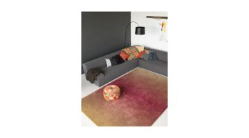 Caméléon vloerkleed met kleurverloop van roze naar bruin, gestyled in een moderne woonkamer met grijze hoekbank.