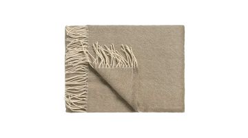  Vandyck Home Benevento plaid in hazel met gemêleerde structuur en franjes, opgevouwen en deels omgeslagen op een witte achtergrond.