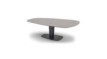 Ovale trapeziumvormige eettafel in grijze houtlook met centrale cilinderpoot en donkere voetplaat