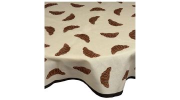 Beige tafelkleed met bruine croissantprint over tafel met donkere rand langs de onderzijde