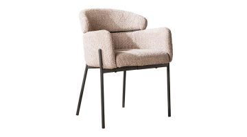 Zandkleurige bouclé armstoel naast een moderne eettafel met decoratieve accessoires.