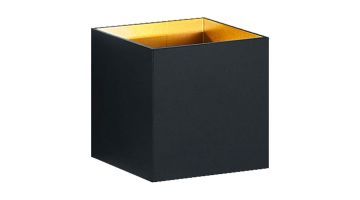 Wandlamp in mat zwart met gouden binnenkant, gemonteerd op een grijze muur, met lichtstralen naar boven en beneden.