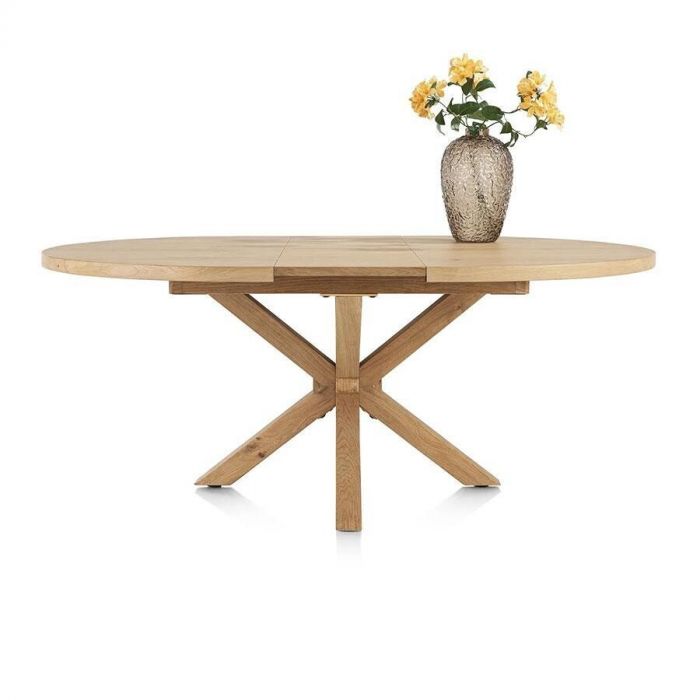 Henders & Hazel Nyborg uitschuifbare eettafel in Deens ovaal design met houten kruisvoet, afgebeeld met vaas met bloemen op het blad.