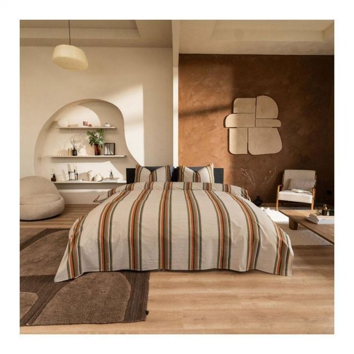 Dekbedovertrek Agui in taupe met kleurrijke strepen van Beddinghouse op een opgemaakt bed in sfeervolle, moderne slaapkamer.