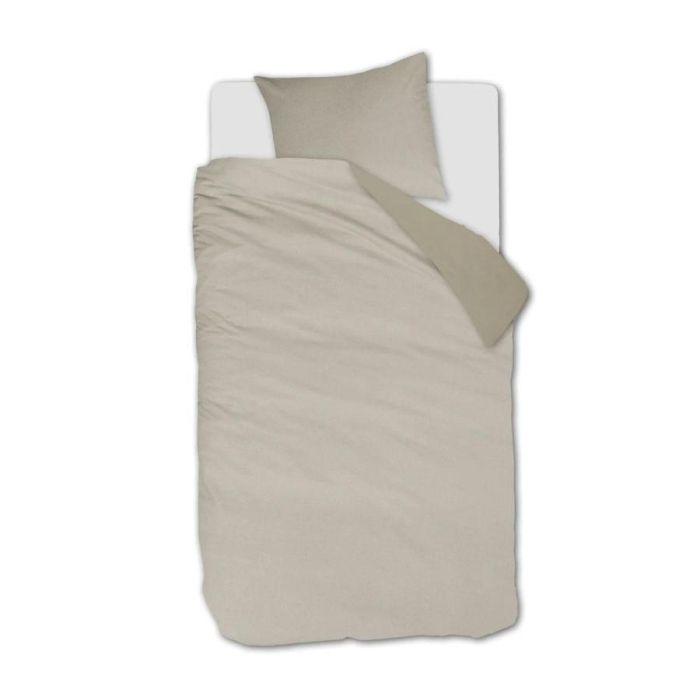 Eenpersoonsbed opgemaakt met het Warm dekbedovertrek in zandkleur, met effen weefmotief en omgeslagen bovenrand in een subtiel andere tint.