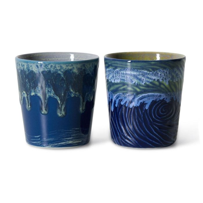 Twee keramieken koffiemokken in diepe blauwtinten met druipglazuur en golvend patroon naast elkaar