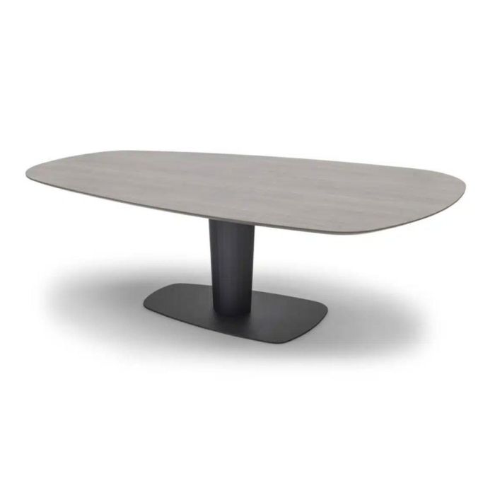 Ovale trapeziumvormige eettafel in grijze houtlook met centrale cilinderpoot en donkere voetplaat