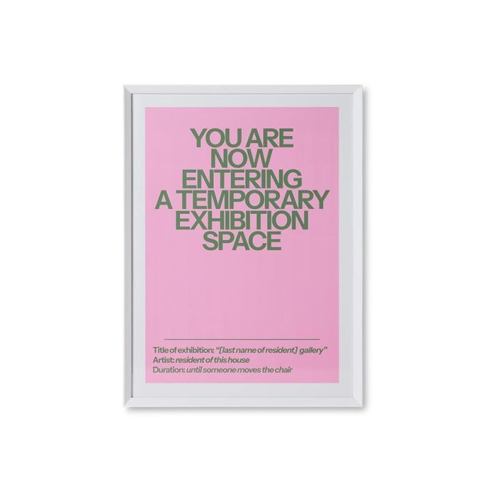 Roze poster met witte tekst en witte lijst, staand tegen een muur