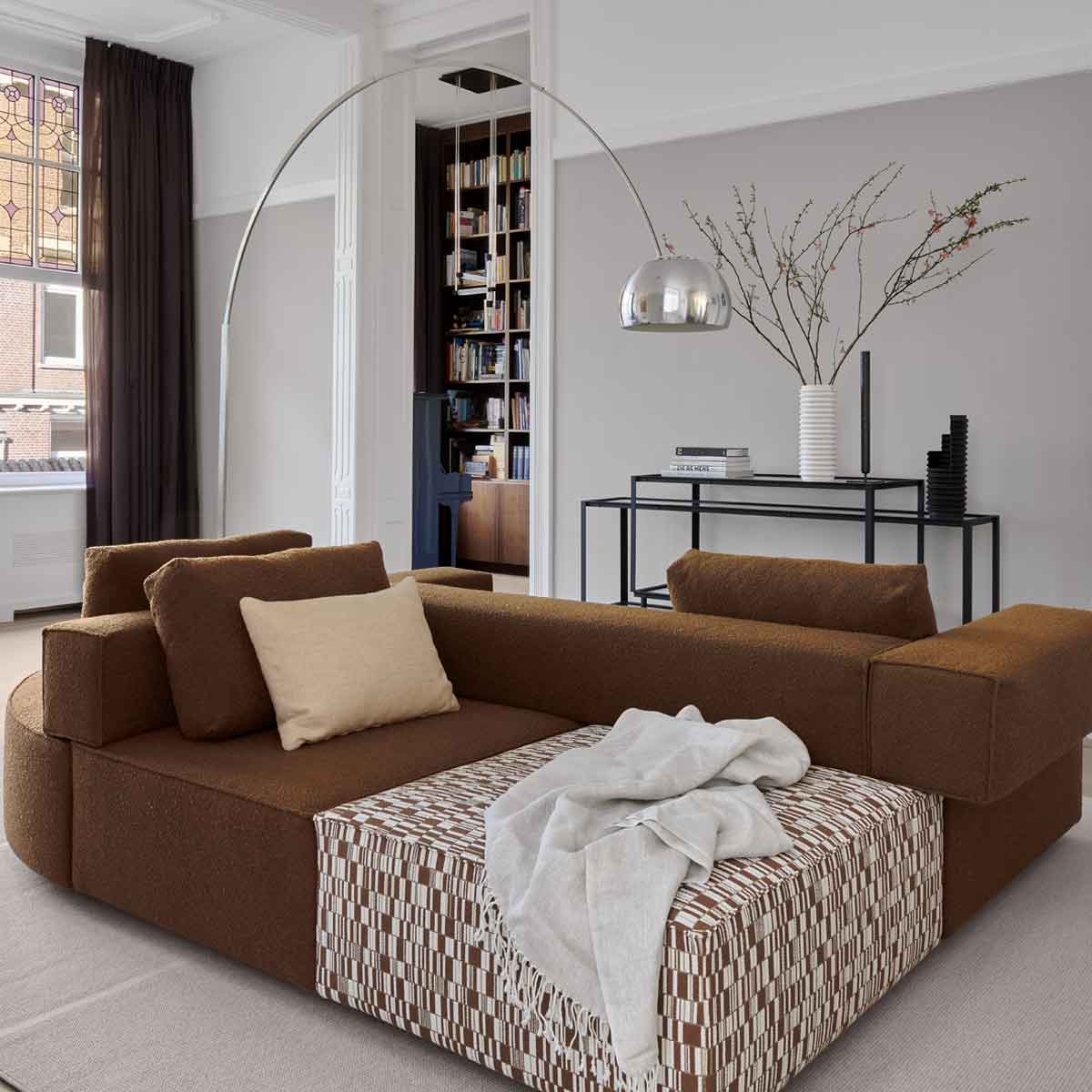 Rode designbank van Gelderland Design met strakke belijning in moderne woonkamer met grote ramen, geel gordijn en zwart leeslampje