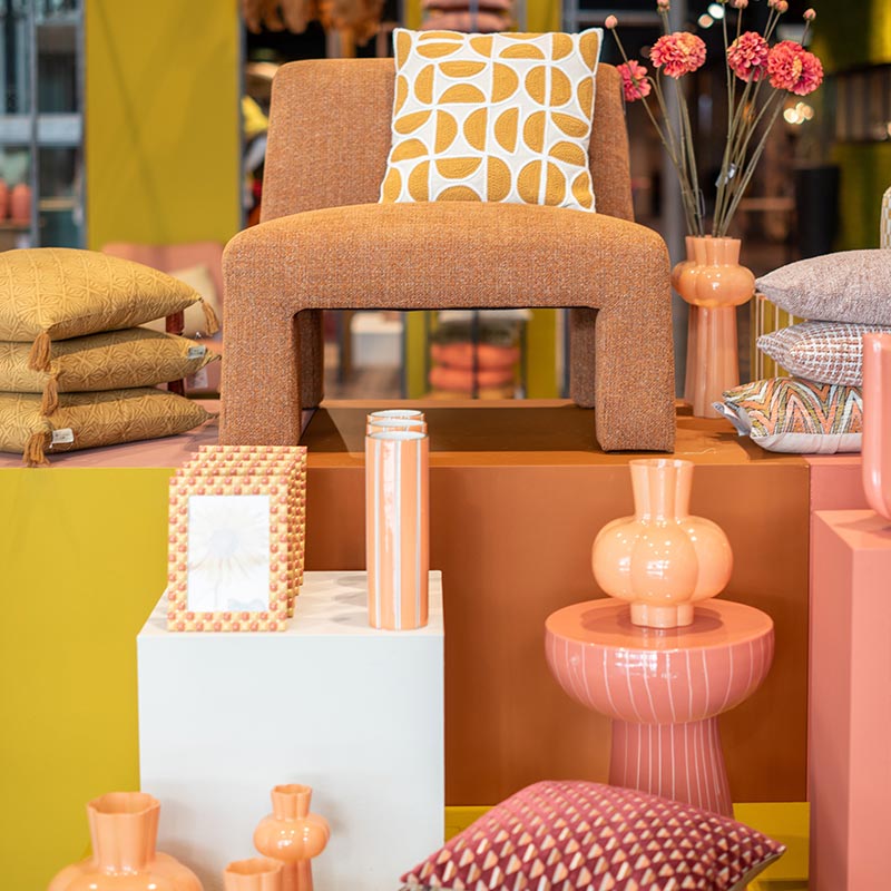 Modern Retro interieur met warme perziktinten, mosterdgele accenten en speelse grafische patronen. Een mix van organische vormen, keramische accessoires en fluweelzachte stoffen