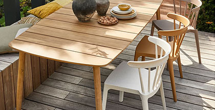 Houten tuintafel met moderne kunststof tuinstoelen in groen, wit en zwart, sfeervol gedekt voor buiten