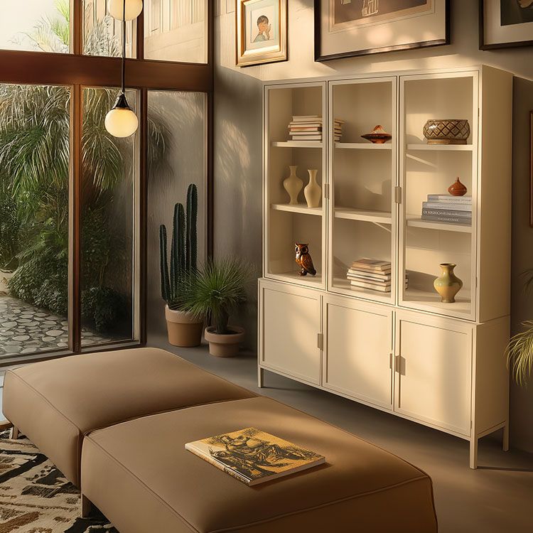 Interieur met New Routz vitrinekast in beige, ingericht met boeken en keramiek, naast grote ramen en groene kamerplanten.