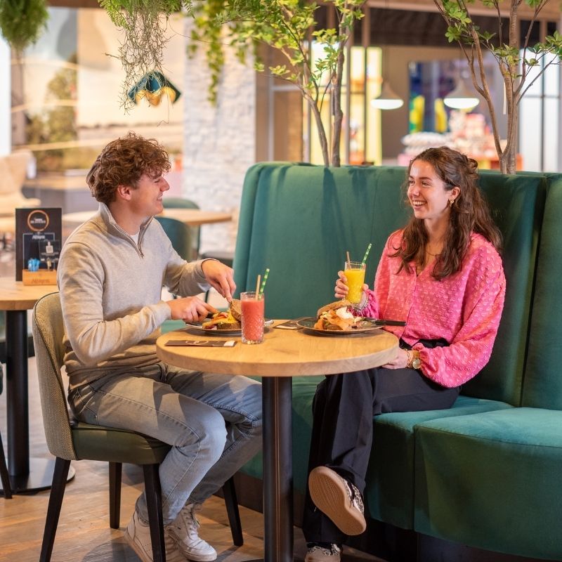 Een man en vrouw genieten van een lunch en een drankje in de Home Brasserie