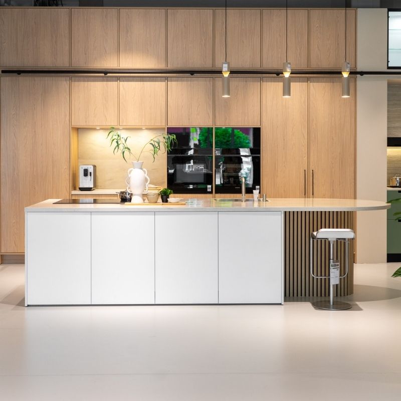 Moderne witte keuken in de Keukenboulevard met een houten kastenwand op de achtergrond