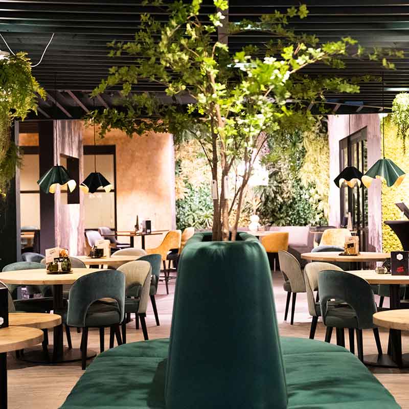 Een groene zitbank, houten tafels en stoelen in het restaurant