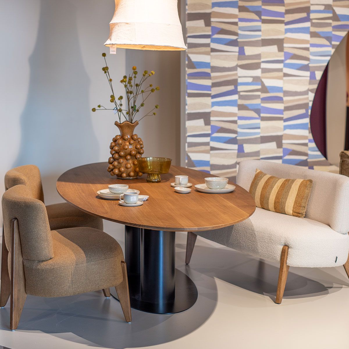 Design fauteuil met opvallende bruine print naast zwarte vaas met kale takken