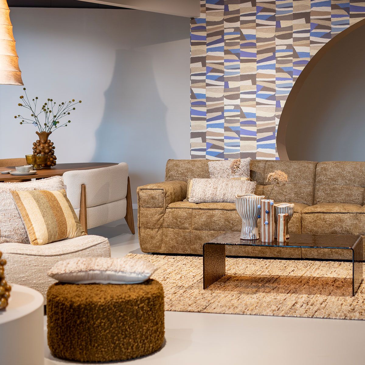 Blauwe en beige woonaccessoires met geweven textiel, keramiek en bloemen op een rustieke ondergrond.