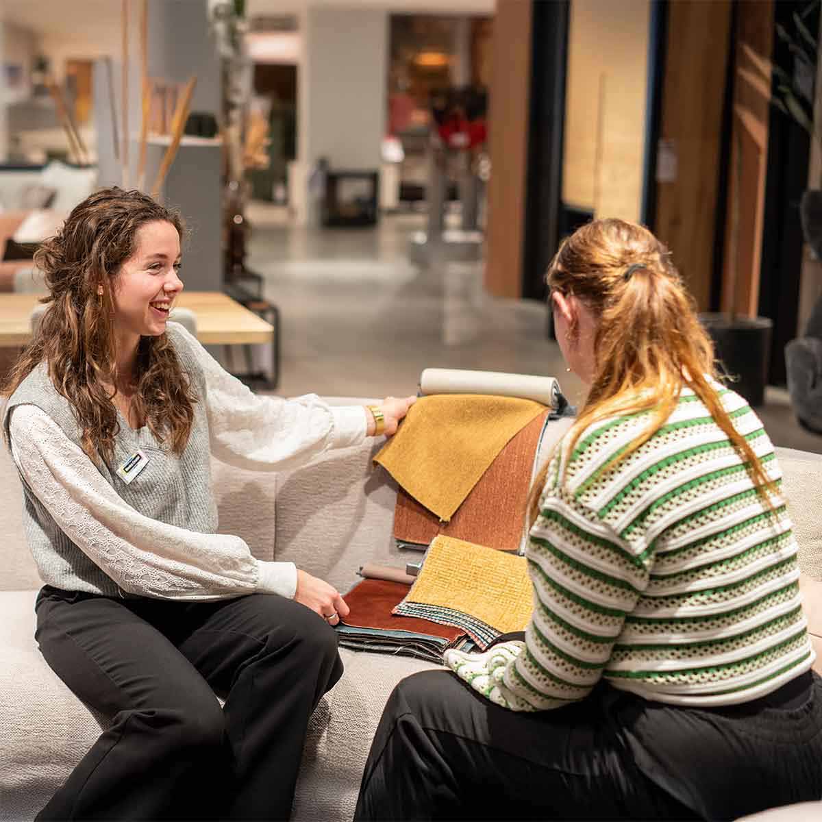 woonadviseur laat stofstaaltjes zien aan een klant midden in een woonwinkel