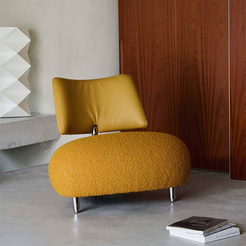 Gele design fauteuil met organische vormen in modern interieur met houten wandpanelen