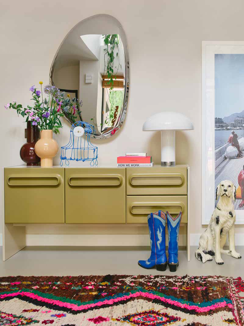 Eclectisch interieur met kleuren en een groene wandkast vol accessoires en spiegel