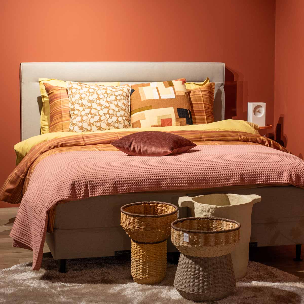 Foto van een opgemaakt bed in de woontrend Blush & Bold met veel oranje, rozige kleurtinten