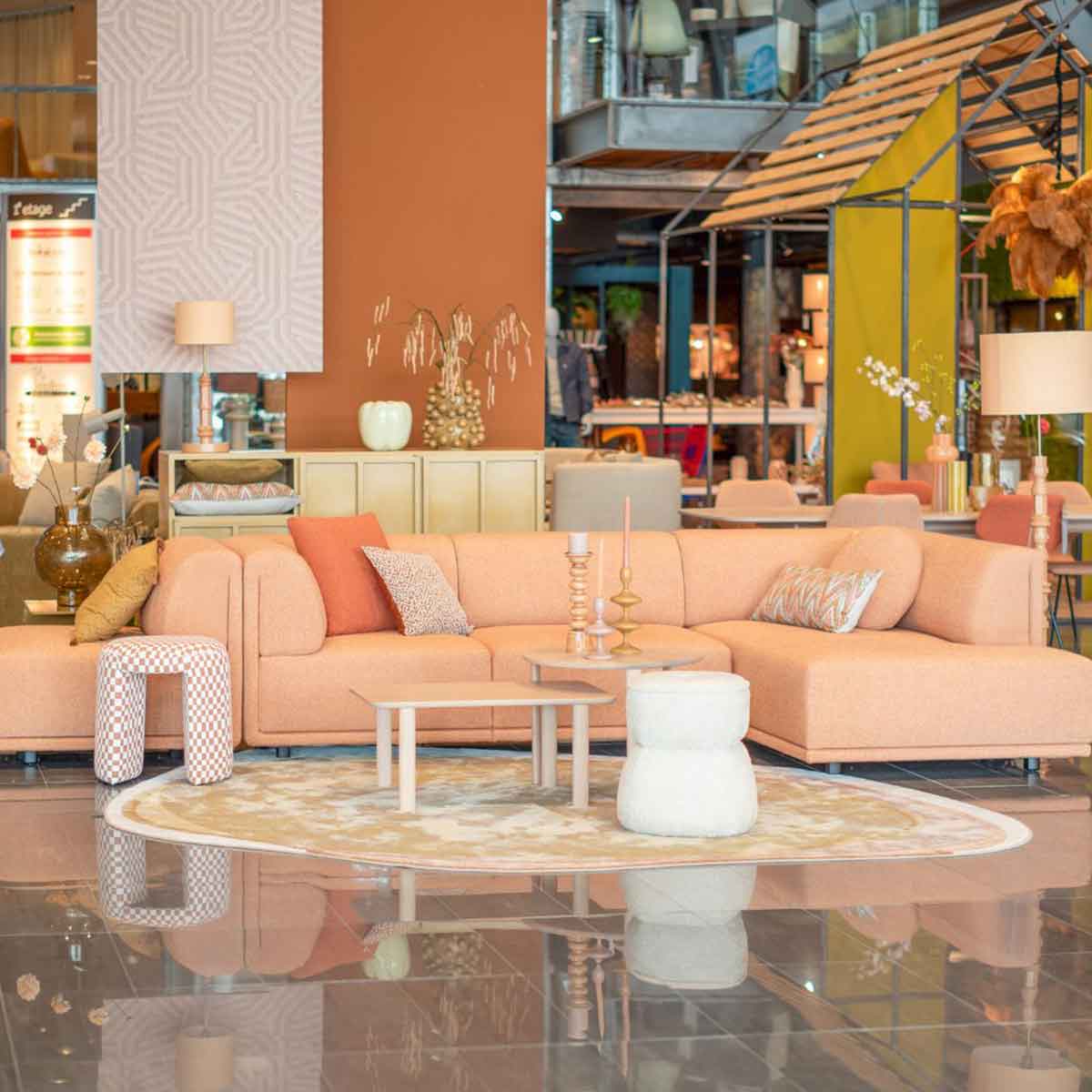 Een koraalkleurige hoek in de hal van Home Center met accessoires, een kleed en bijzettafels