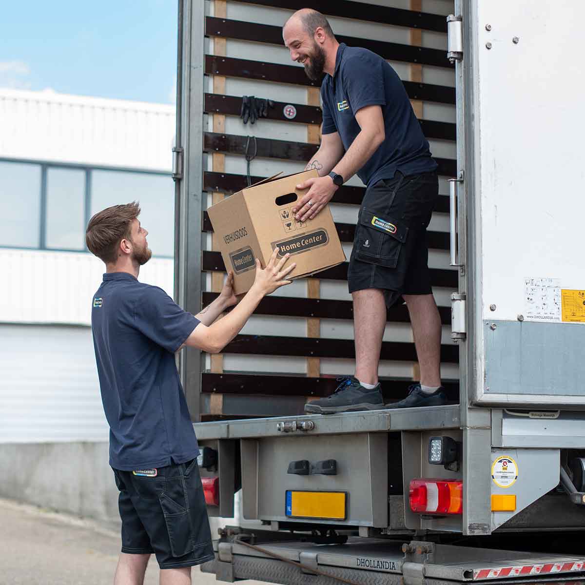 Twee mannen die spullen van Home Center verplaatsen op een vrachtwagen